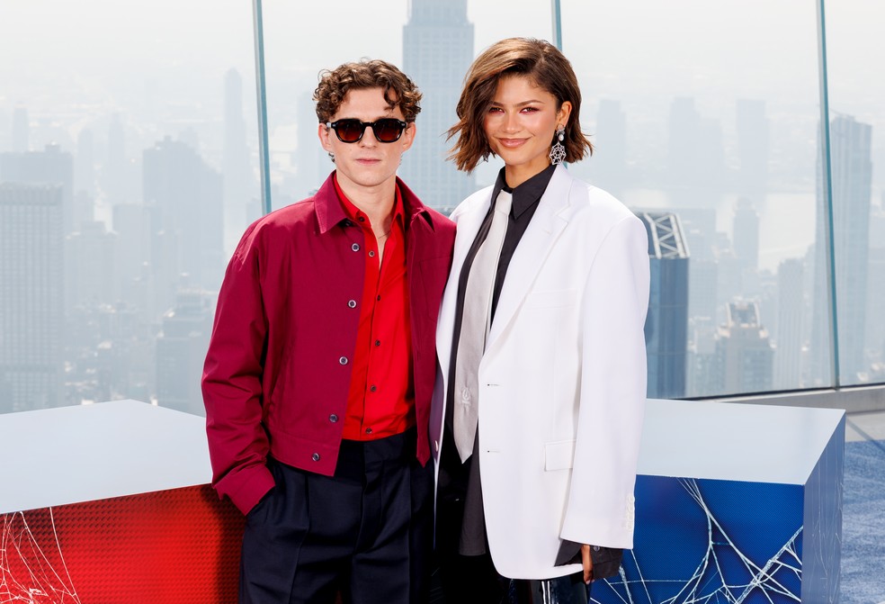 Zendaya rouba a cena com gravata prata e joia temática de Homem-Aranha ao lado de Tom Holland — Foto: Getty Images