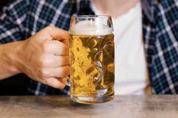 Saiba como a bebida pode afetar o processo de emagrecimento e hipertrofia. um homem segurando um copo de cerveja.