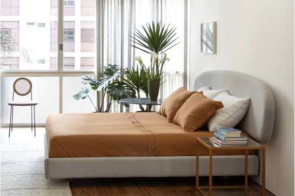 Decorao de quarto: um quarto com uma cama com lenis terrosos em frente a uma janela.