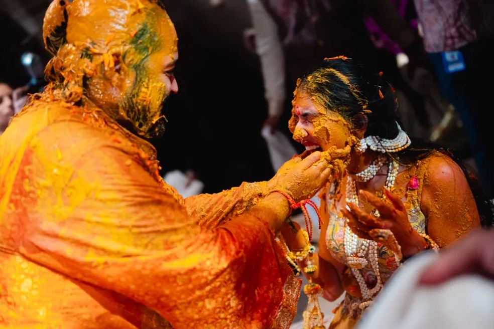 "A cerimônia Haldi é um evento íntimo, onde a pasta de açafrão é aplicada nos noivos. Acredita-se que este ritual abençoa o casal com boa saúde e prosperidade. A atmosfera estava cheia de alegria – e um pouco de caos! – enquanto os membros da família aplicavam haldi em nós e uns nos outros, cantando canções tradicionais" — Foto: Joseph Radhik